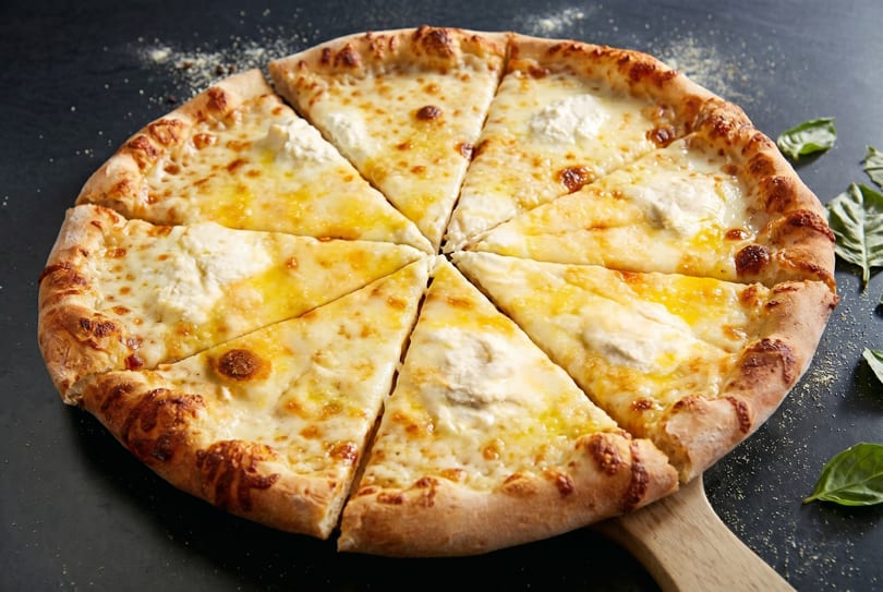 A sliced cheese pizza with a golden crust and melted white cheese on a dark surface.